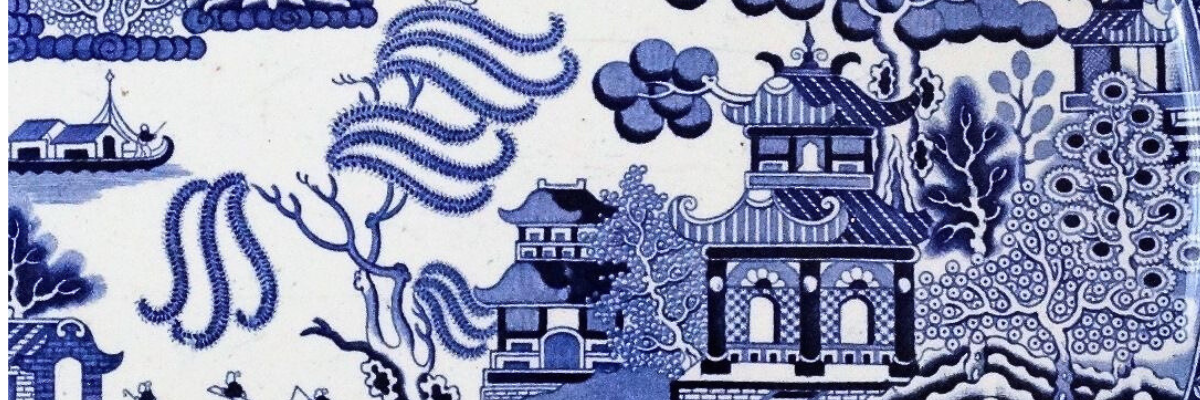Closeup of antique Blue Willow platter featuring detailed pagoda temple with distinctive upturned roof and intricate landscape