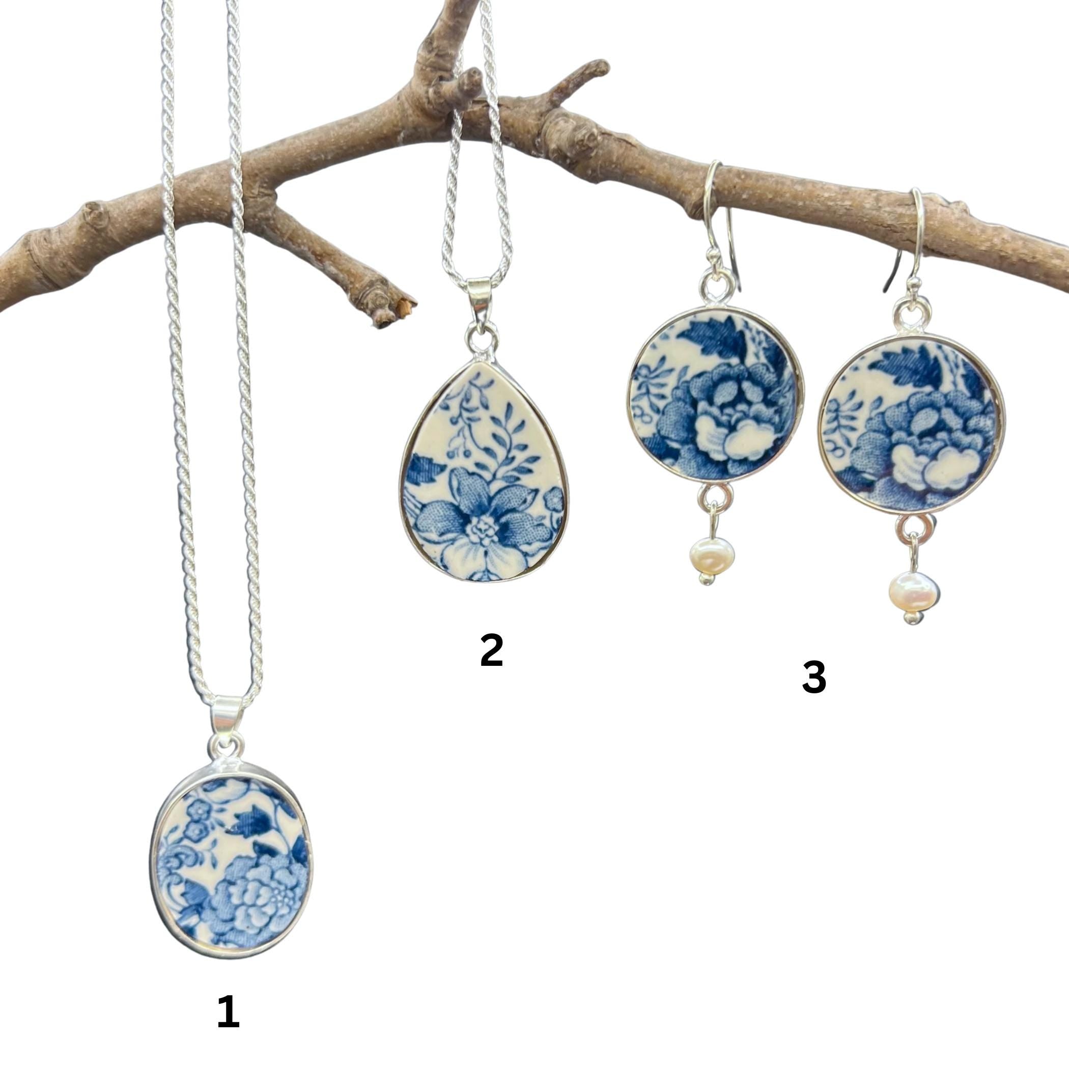 Blue and white Staffordshire china necklace and earrings hanging from a branch, showing the earrings, pendant shapes and sterling silver chain.