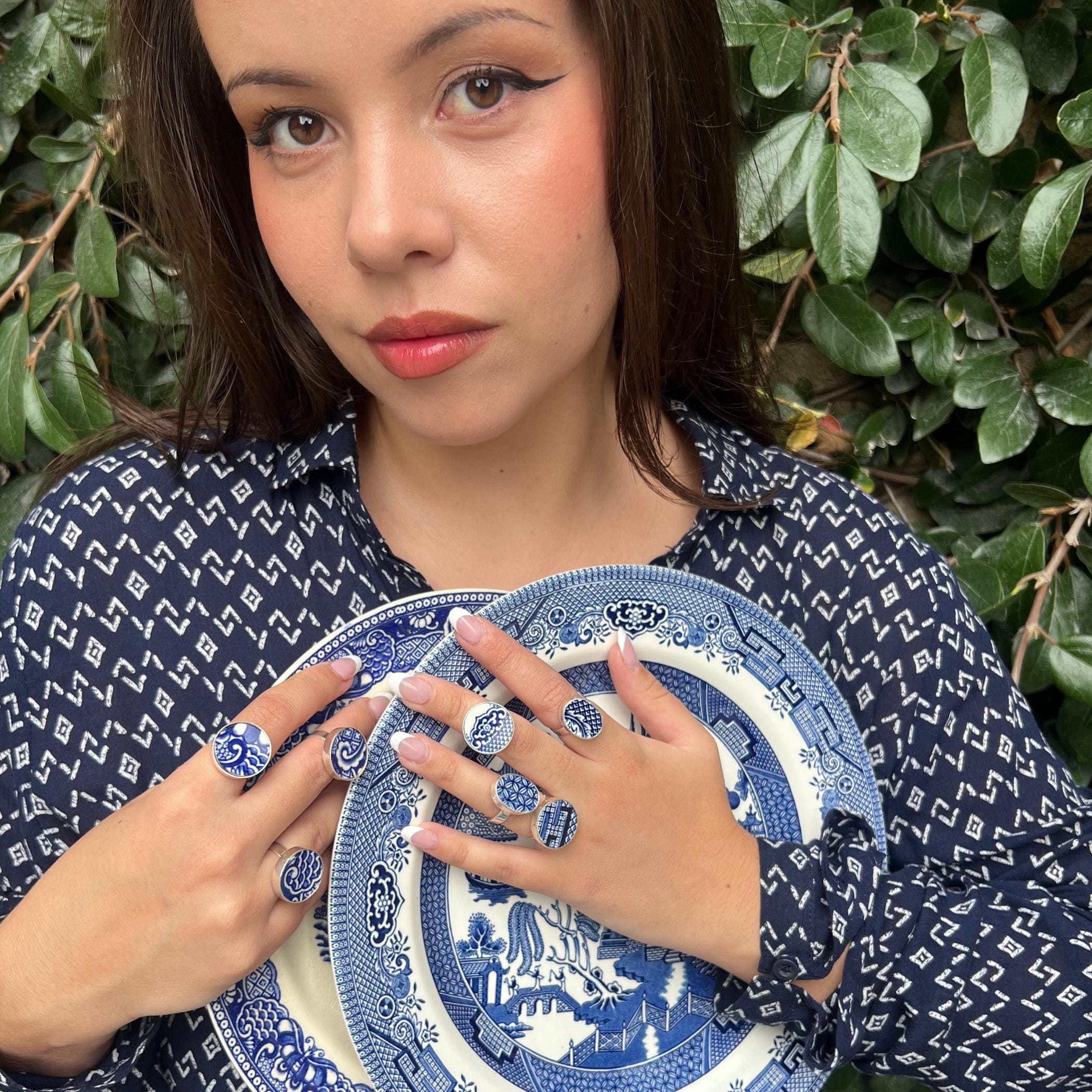 Model wearing multiple vintage Blue Willow china rings from the 2026 collection, stacked across different fingers.