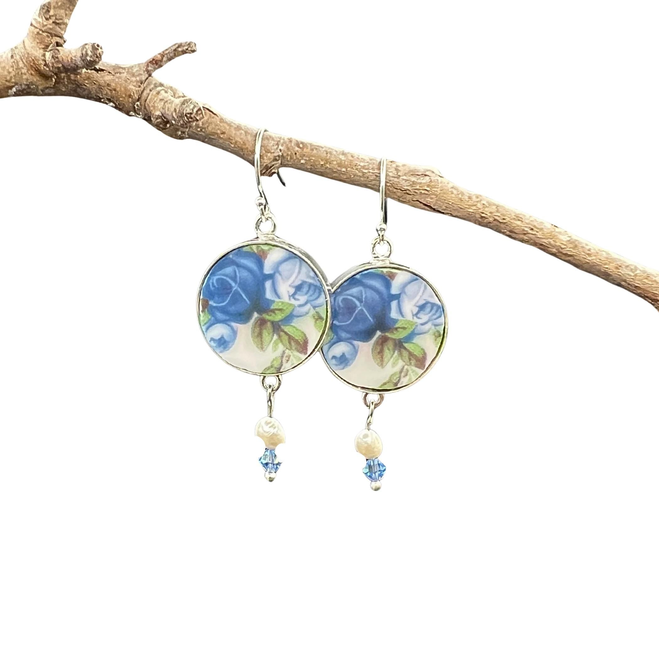 Close-up of Royal Albert Moonlight Rose china earrings showing delicate blue rose pattern, freshwater pearls and crystal elements