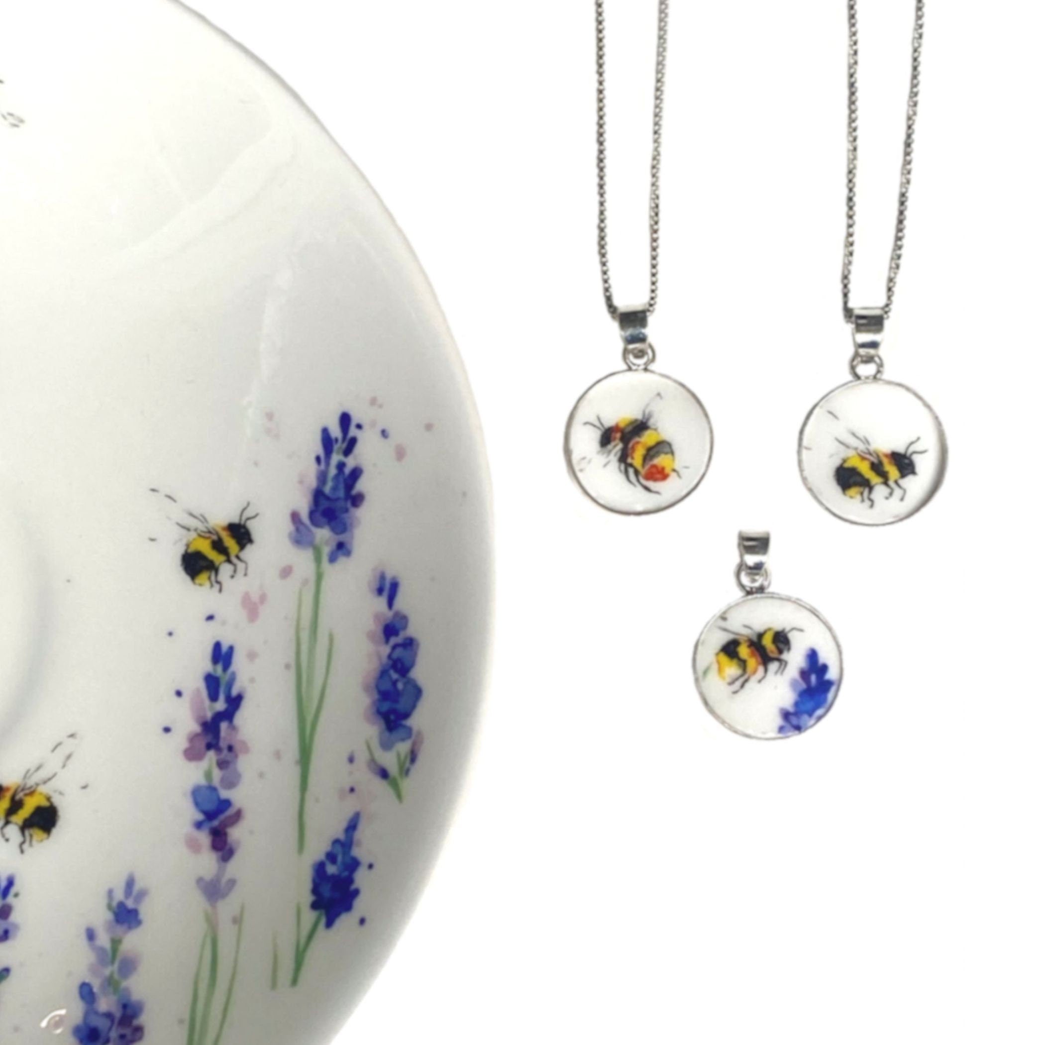 May include: Three silver necklaces with round pendants featuring hand-painted bumblebees on a white background. The pendants are surrounded by a silver frame.