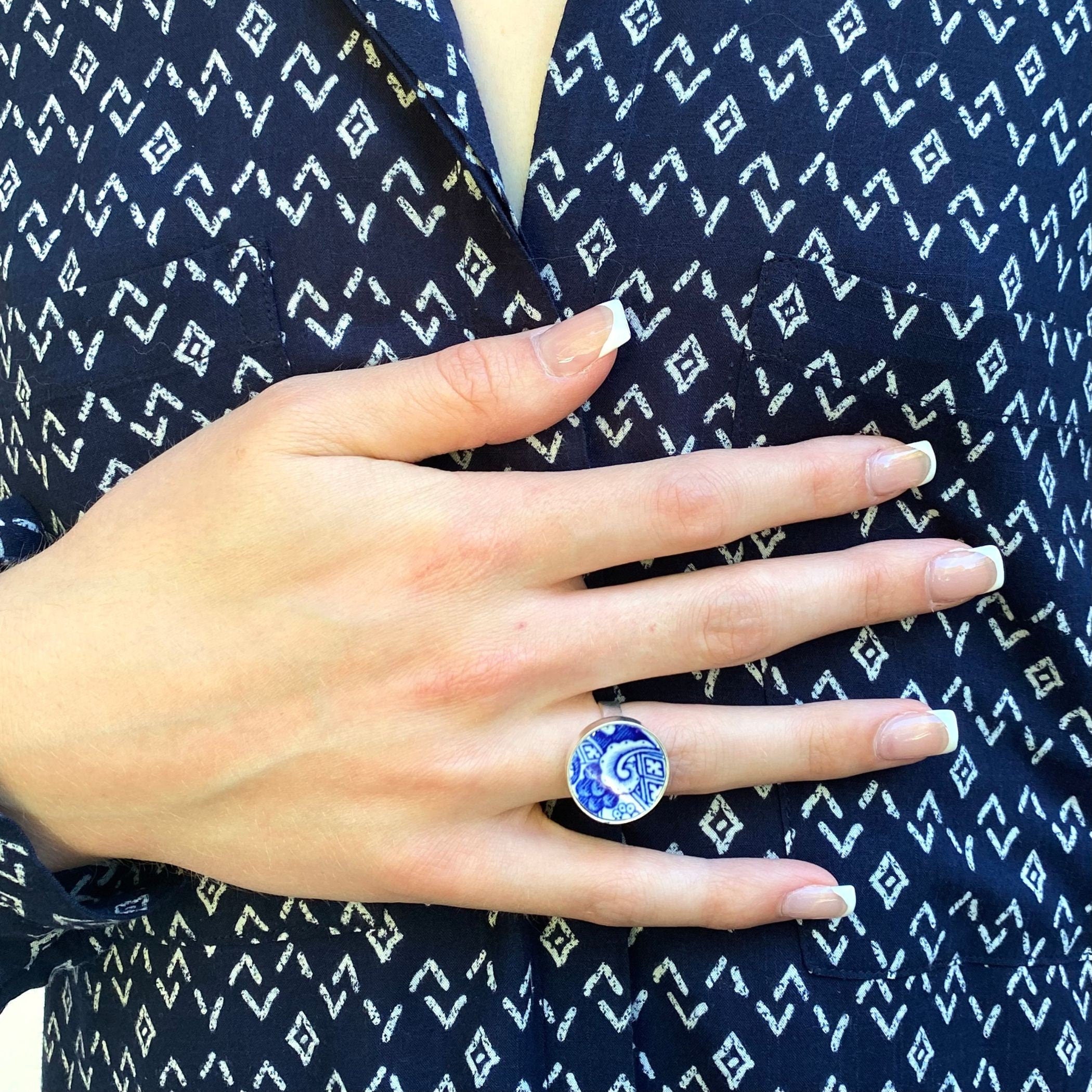 Model's hand wearing a Blue Willow broken china ring in a sterling silver round setting.
