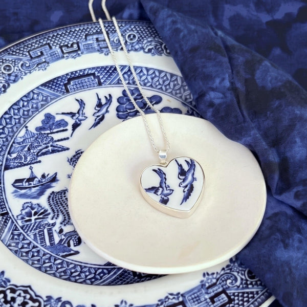 Blue Willow Love Birds heart necklace displayed on the vintage china plate it was cut from.