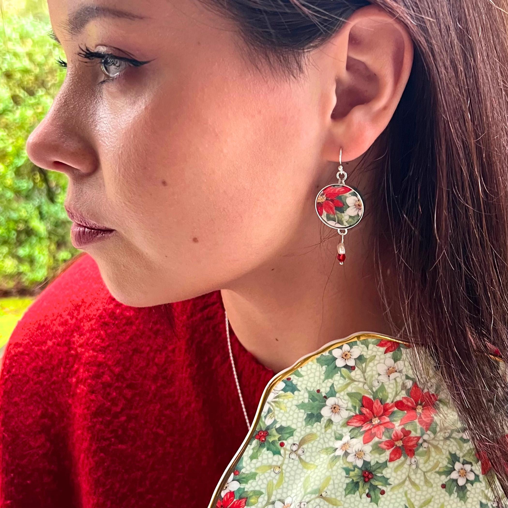 Handcrafted mismatched poinsettia china earrings showing upcycled porcelain detail and festive Christmas design
