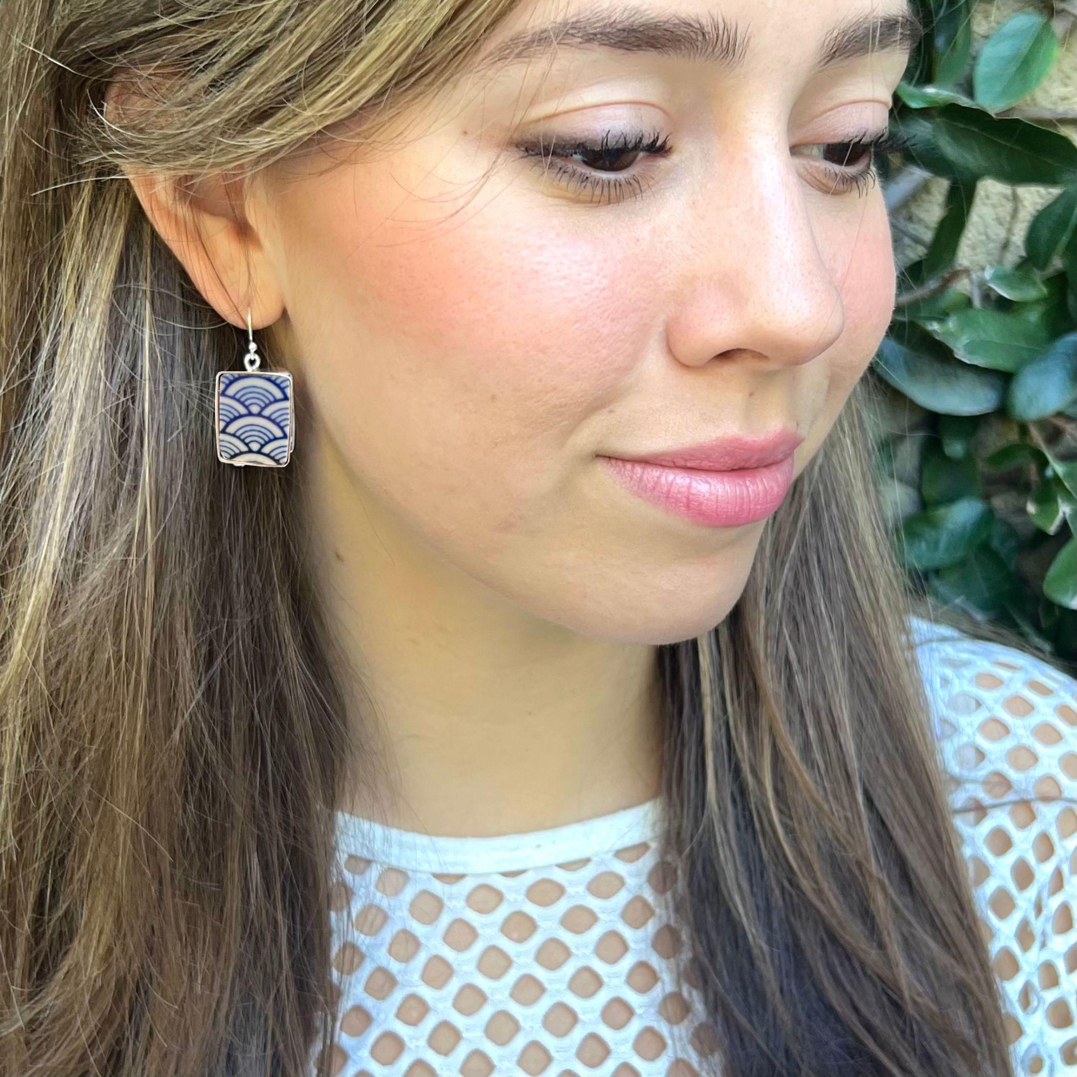 Model wearing blue and white seikaiha wave dangle earrings handmade with upcycled Japanese porcelain. Artisan repurposed jewelry