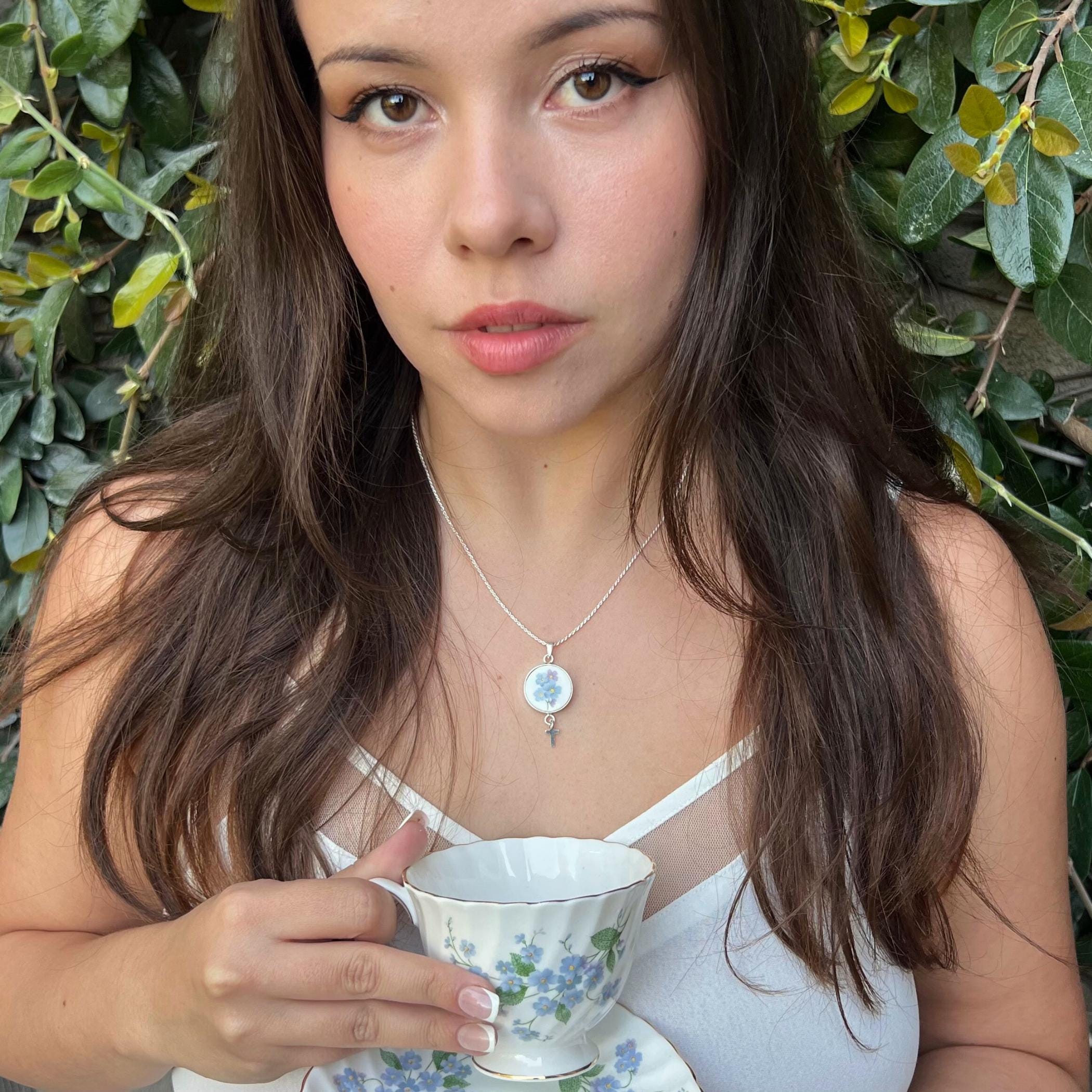 Dainty sterling silver cross necklace with forget me not china pendant worn by woman, meaningful Christian gift for her