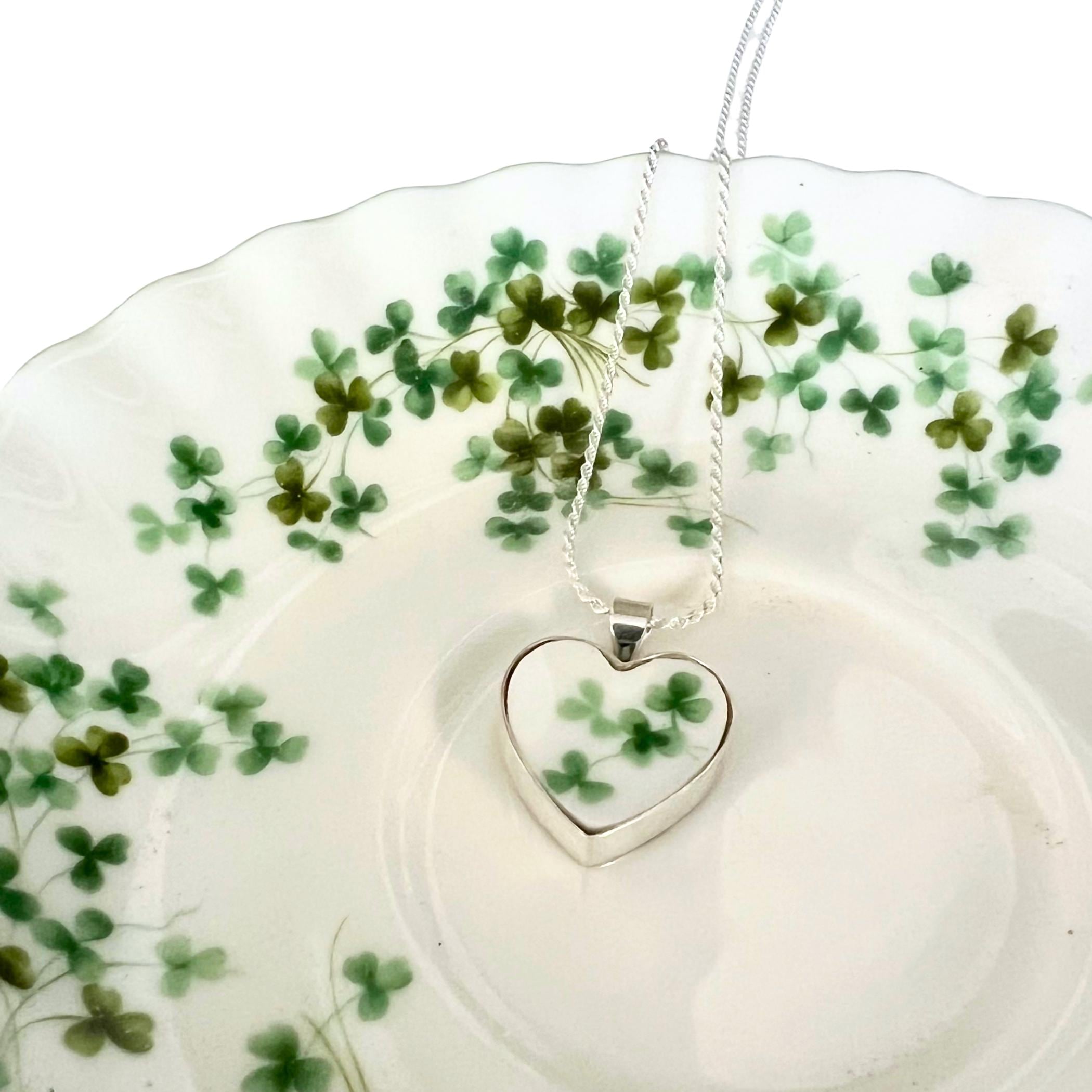 Delicate heart-shaped pendant featuring shamrock pattern from vintage Royal Albert china in sterling silver setting with rope chain.