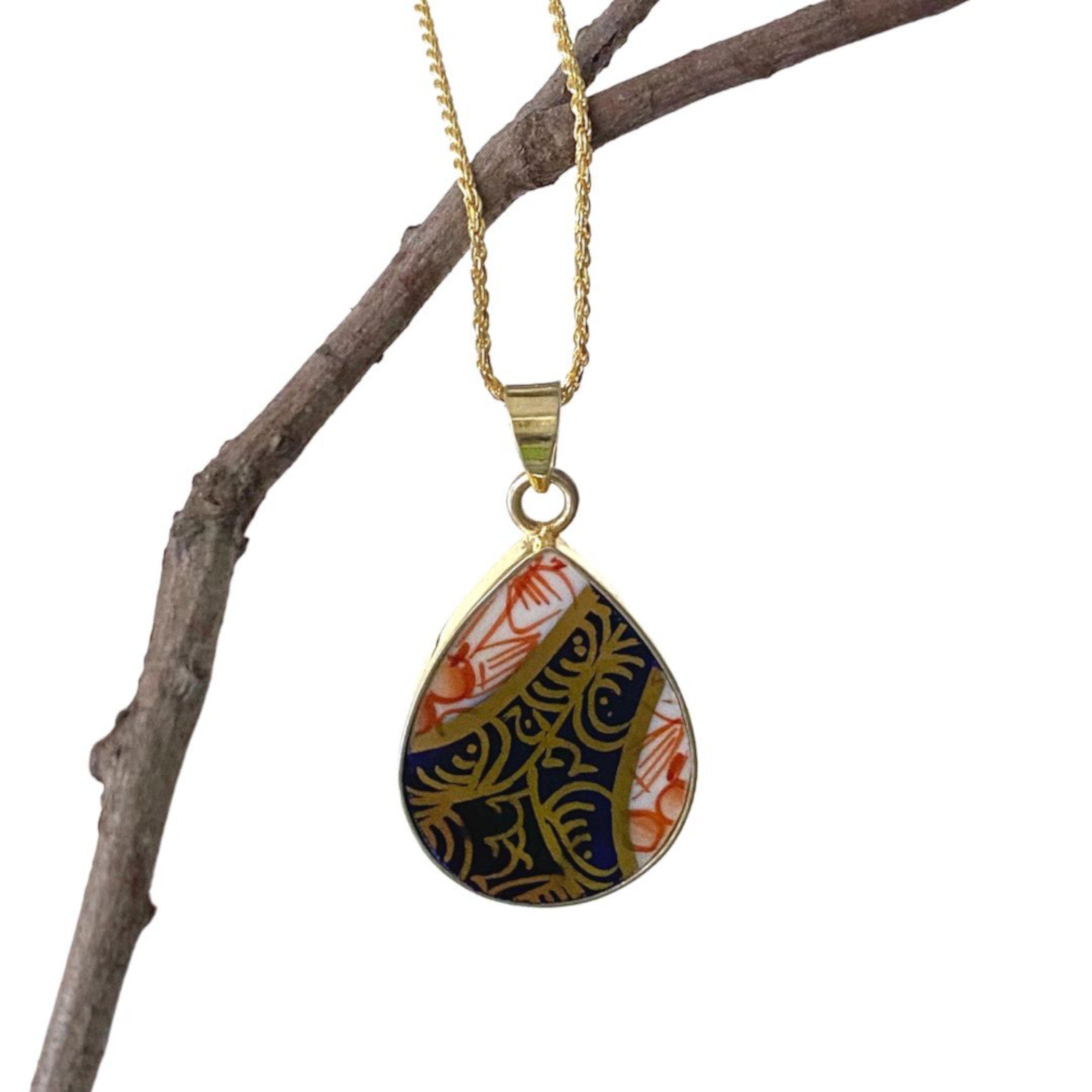 Royal Crown Derby Old Imari china pendant necklace hanging on a branch, showing the gold plated sterling silver setting.