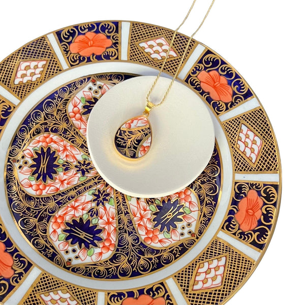Intricate Royal Crown Derby Old Imari porcelain teardrop pendant necklace displayed on the antique plate it was upcycled from.