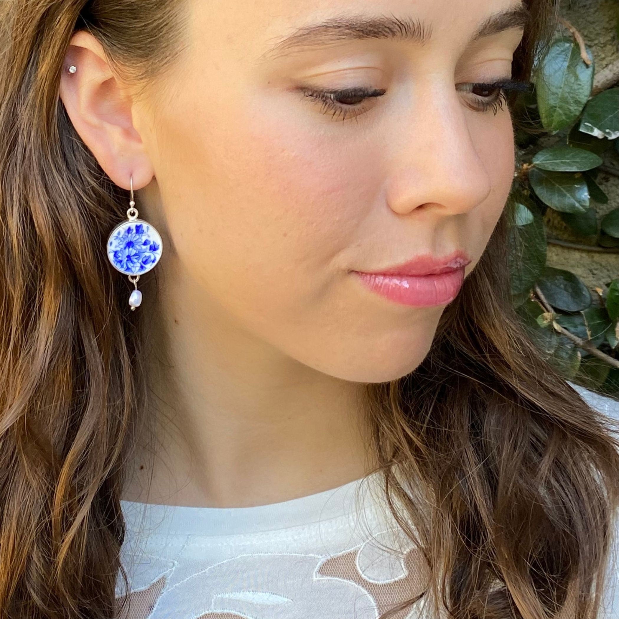 Shelley Dainty Blue china earrings worn on the model, showing the size as well as the blue and white floral pattern set in sterling silver.