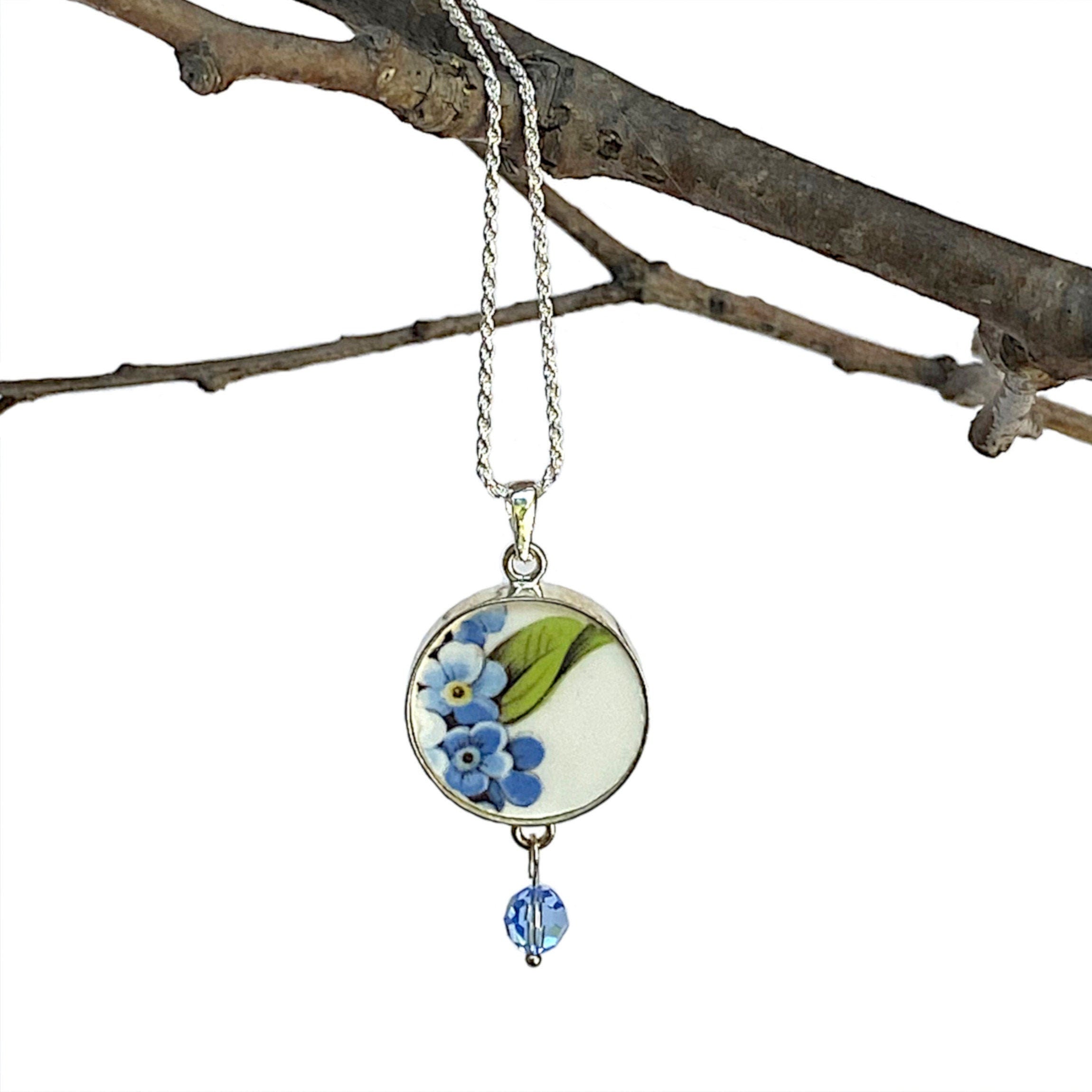 Forget Me Not China Necklace, a diamond cut sterling silver rope chain with, a sterling silver pendant setting, dangling pale blue Swarovski crystals, and a repurposed china piece from a vintage Regency forget me not china plate.